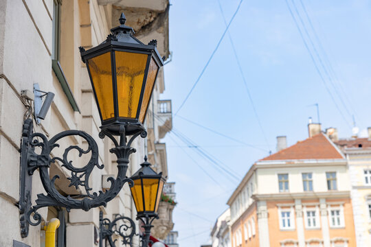 Vintage wall-mounted street lanterns with yellow glass on an old building facade in Lviv