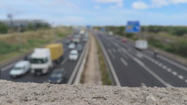 Blurry highway traffic flowing with cars and trucks viewed from an overpass, depicting commuting, transportation, and daily travel in a busy urban environment