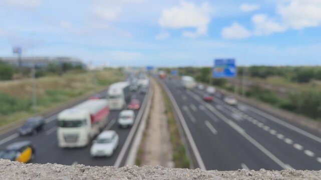 Blurred highway scene showing morning rush hour traffic congestion with cars and trucks driving on the road, creating an anonymous and abstract urban transportation concept