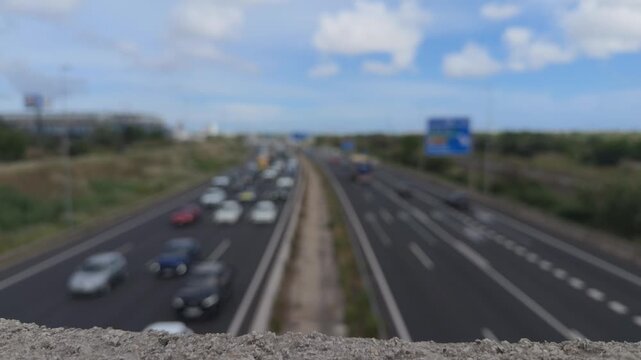 Blurry highway traffic with cars and trucks driving under a blue sky, showcasing the daily commute, transportation logistics, and the concept of modern urban mobility