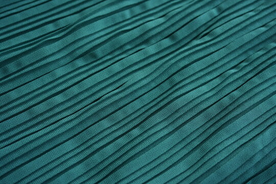 Turquoise pleated fabric texture background  pleated fabric with elegant parallel folds and flowing lines. Vibrant textured textile creates a stylish abstract background ideal for fashion branding