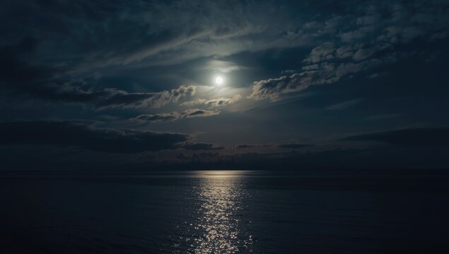Calm Seascape Under Super Moon Nighttime Sky with Moving Clouds, Reflective Water