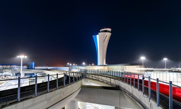 San Francisco, California - July 3, 2025: Night view of motion-blurred train and illuminated Air Traffic Control tower at San Francisco International Airport in the United States