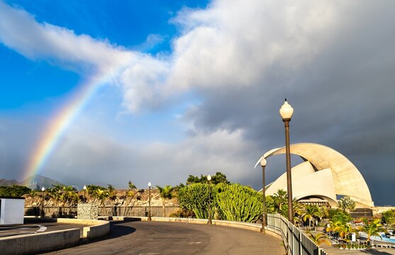 Santa Cruz de Tenerife, Spain - January 16, 2026: Scenic view of a beautiful rainbow over the iconic white curves of the Auditorio de Tenerife and palm trees in Tenerife, Canary Islands.
