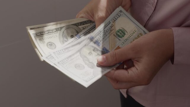 An unrecognizable woman counts American dollar bills close-up.