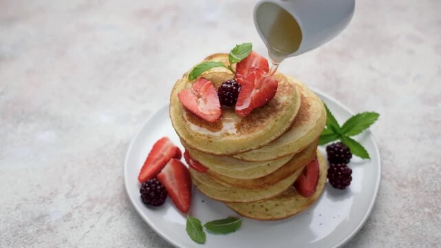 Pouring maple syrup on a delicious pancakes stack