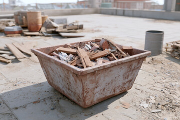Fototapeta premium Construction site cleanup with debris container and scattered materials, realistic detail.