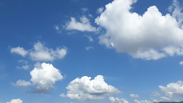 Fluffy white clouds moving across a vibrant blue sky