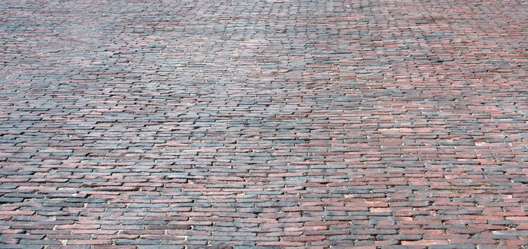 Brick pavement texture shows urban character. Brick surface reveals historic street pattern. Brick road highlights rough stone detail. Brick background supports design usage.