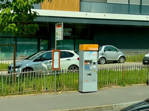 Geneva, switzerland - June 13 2025: A tag ticket machine stands on a sidewalk near parked cars in Switzerland. Daytime outdoor location.