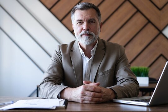 Smiling mature business man executive wearing shirt sitting at desk using laptop. Happy busy professional middle aged manager investor working on computer in office