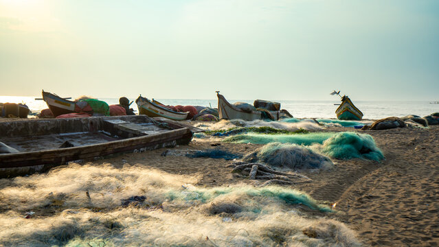 Cluster of fishing boats and tangled nets on beach during golden hour capturing the scale of traditional fishing operations along coastline