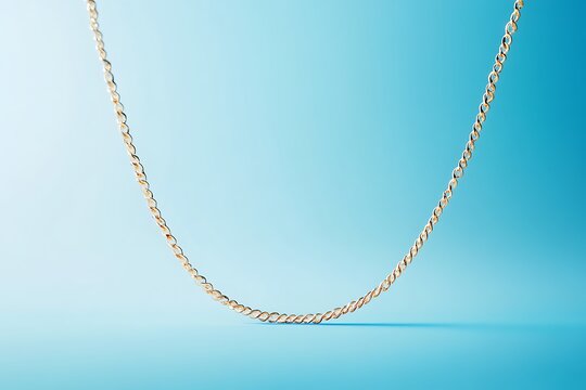 Elegant gold figaro chain necklace on light blue background minimalist jewelry product shot