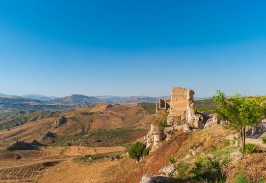 The Barresi Castle in Pietraperzia, Italy. Mountainous landscape with ruins of a fortress in the foreground.