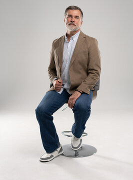 full body picture of happy elegant mature man sitting, laughing in front of white