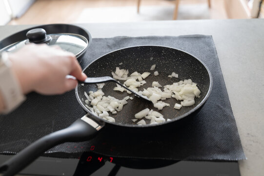 Candid shot of someone stirring onions on induction cooktop during weekday meal