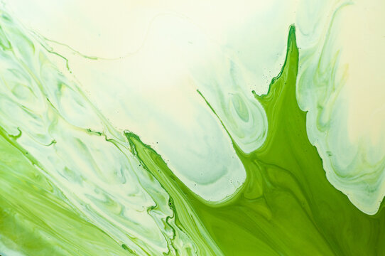 Green liquid swirls create patterns on a surface during a creative activity indoors