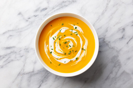 Pumpkin, butternut squash soup in bowl. White marble background. Close up. Top view.