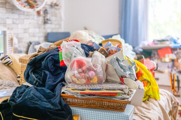 Bed covered with tangled holiday ornaments plastic bags clothes baskets boxes toys blankets creating chaotic scene suggesting post celebration cleanup, transformation hoarding stress domestic disorder © kittyfly