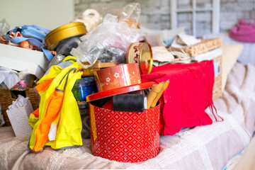 Bed covered with tangled holiday ornaments plastic bags clothes baskets boxes toys blankets creating chaotic scene suggesting post celebration cleanup, transformation hoarding stress domestic disorder © kittyfly