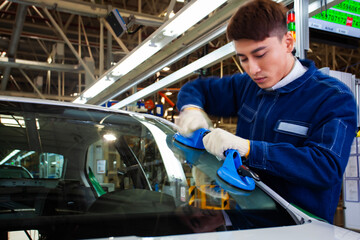 Fototapeta premium Asian workers at a car factory are installing car windows.