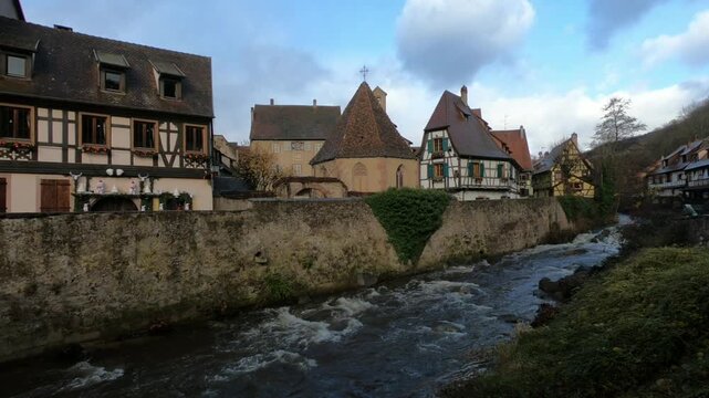 The Weiss river running between half timbered houses, Kaysersberg, Alsace, France, Europe. River with strong current flowing through the rocks.