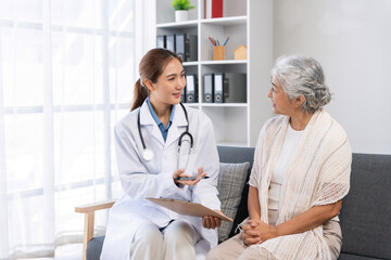 Female doctor talking with senior woman during a home medical consultation, providing professional healthcare and support © amnaj