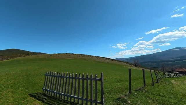 Sunlight warms a green hillside under vast blue sky. Mount Goc, Ljukten peak. Balkans, Serbia
