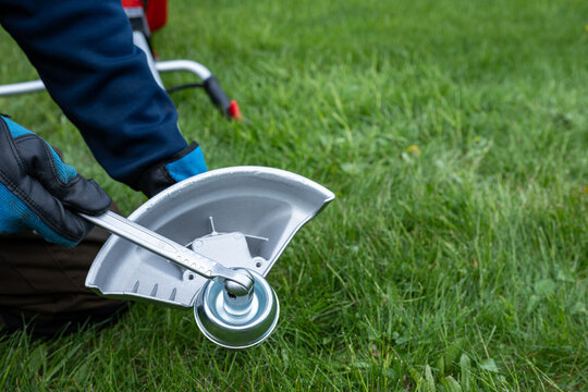 Tightening brushcutter trimmer head with wrench during garden tool maintenance