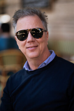 Senior man sitting at table at sidewalk cafe and relaxing