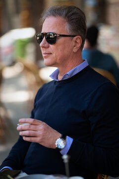 Stylish mature man enjoying coffee at a sidewalk cafe