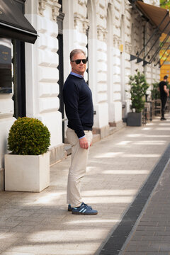 Elegant man in smart casual attire posing by a storefront