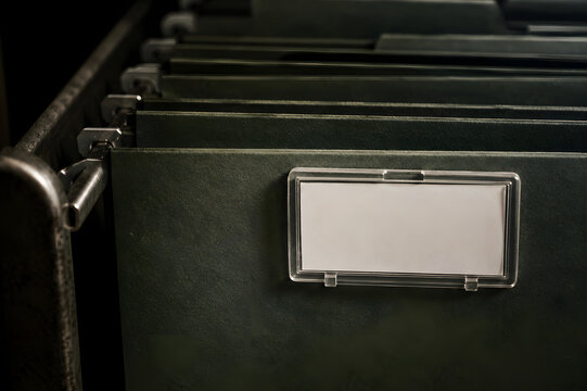 White empty label placed in plastic holder on green hanging file folder