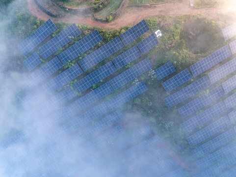 Aerial view of solar power station in misty mountain terrain with green energy panels