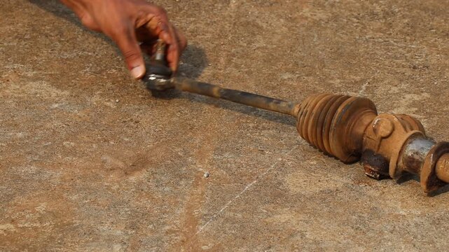 Steering tie rod end in used condition with dirty rubber boots held in the hand