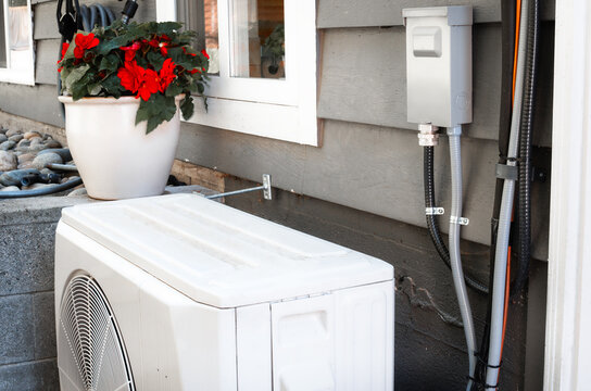 Heat pump outside of home with AC disconnect. HVAC system for heating and cooling with thermal energy transfer. High efficiency heating system. Vancouver, BC. Selective focus.