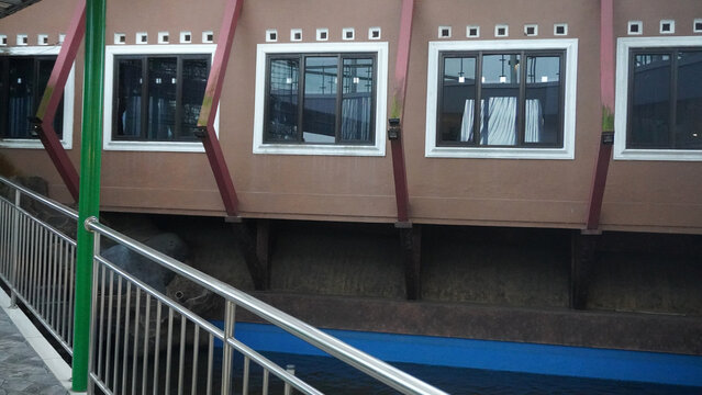 Guesthouse rooms with large windows, steel railing corridor, and colorful exterior. Clean, simple lodging facade ideal for travel, hospitality, and accommodation themes.