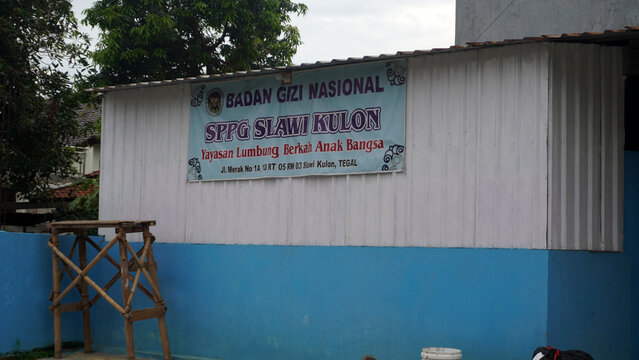 Tegal, Indonesia - 23 March 2026: Small white-blue building with banner of Badan Gizi Nasional SPPG Slawi Kulon.