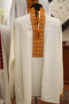 An old traditional Ukrainian vyshyvanka shirt, hand-embroidered by prisoners, is displayed in a museum of Soviet repression, reflecting suffering, resistance, and memory within former NKVD and KGB pri