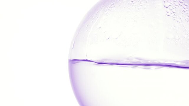 Tight zoom on crystal-like liquid boiling in a round-bottom flask, producing bubbles and condensation on its wall with white background