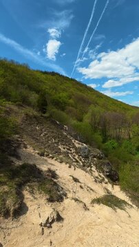 Sunlit trail winds through green hills. Bigar Waterfall, Serbia. Vertical