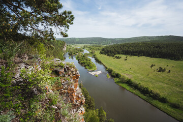 Obraz premium Tranquil nature scene. Calm retreat with lush trees overlooking gentle river and sky. Quiet woodland canopy provides perfect setting for relaxation and digital break near water