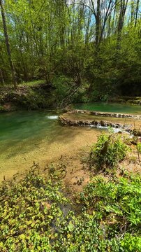 Rocks and moss line the shallow. Bigar Waterfall, Serbia. Vertical