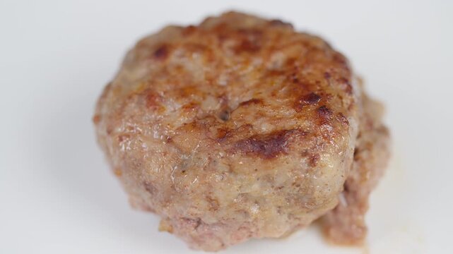 Closeup of crispy meat patty. Plate featuring browned crust and shiny meat juices closeup. Studiostyle display of textured meat patty with golden crust and succulent juices