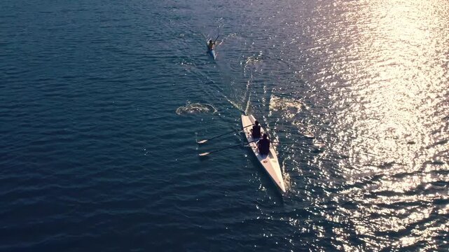 Drone shot of kayakers and rowers moving across sunlit lake water with bright reflections and ripples. Scenic outdoor sport scene showing teamwork, training, freedom and nature.