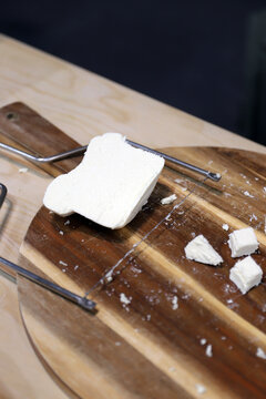 trozos de queso fresco artesanal de Cebreiro, partidos en una tabla de madera con lira