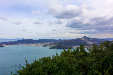 Obraz premium Panoramic coastal landscape of Seto Inland Sea and mountains beneath dramatic clouds in Shikoku Japan
