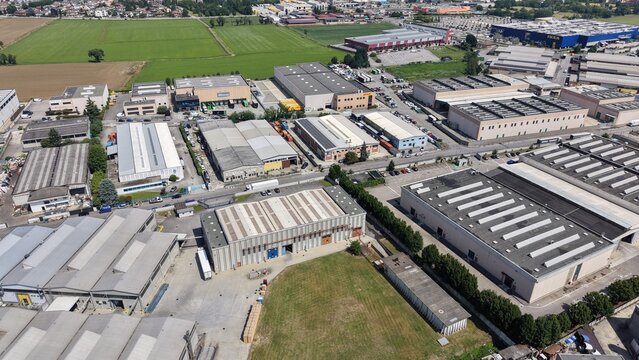 Drone footage of a manufacturing district in Northern Italy near Milan. Industrial buildings, production sites and logistics infrastructure viewed from above.