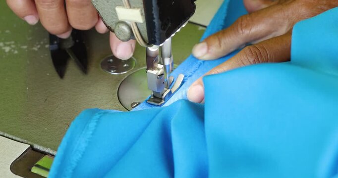 Hands sewing blue fabric with a sewing machine, close-up. Sewing machine, highlighting craftsmanship, tailoring precision, fashion production, textile industry, and handmade clothing process