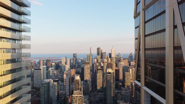 Descending between modern office buildings and apartments reveals Toronto's skyline at golden hour with contemporary towers and Lake Ontario on the horizon